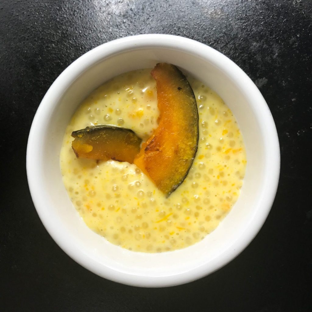 A bowl of pudding with a slice of pumpkin in it.