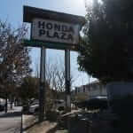 A honda plaza sign sits on a street corner.