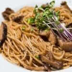A plate of spaghetti with mushrooms and herbs.