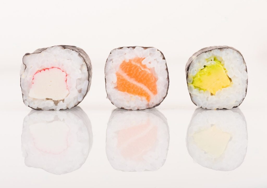 Four different types of maki sushi on a white background.