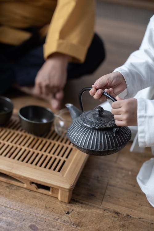 hands holding an iron tea pot