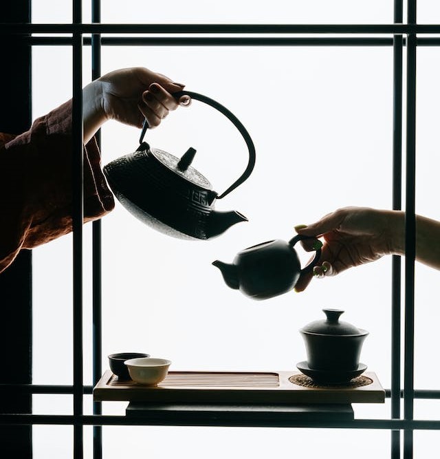 hands showcasing two different tea pots
