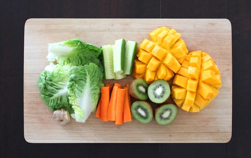 wood cutting board with sliced vegetables and mango 