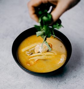 A keto-friendly bowl of miso soup with a hand reaching into it.