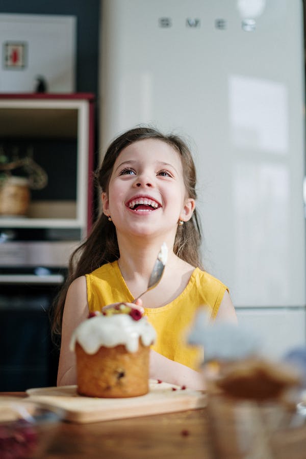 A little girl is joyfully eating a cake made with native vanilla beans.