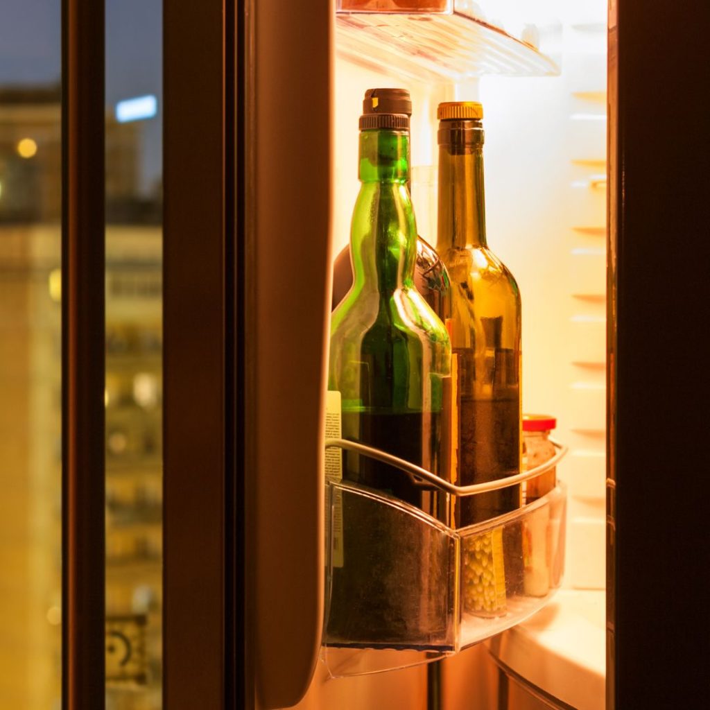 Bottles of olive oil are stored in a refrigerator.