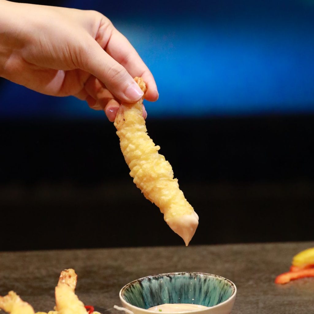 hand dipping tempura in a sauce