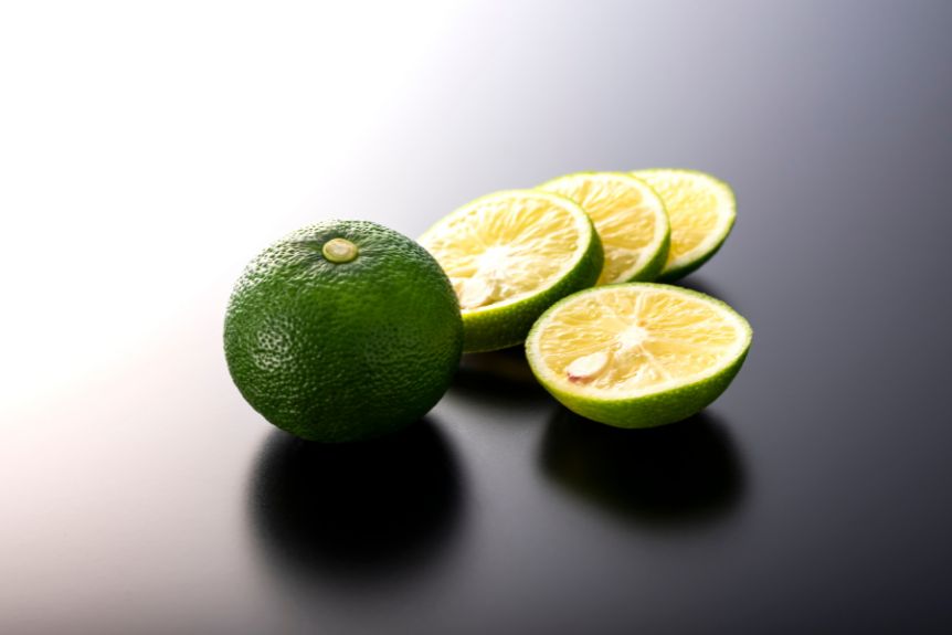 Sudachi and some slices in a black surfaces is one of the Japanese citrus varieties.