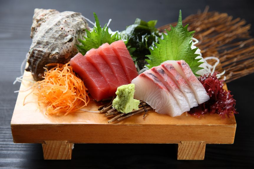 Sashimi Japanese fish varieties on a wooden board.