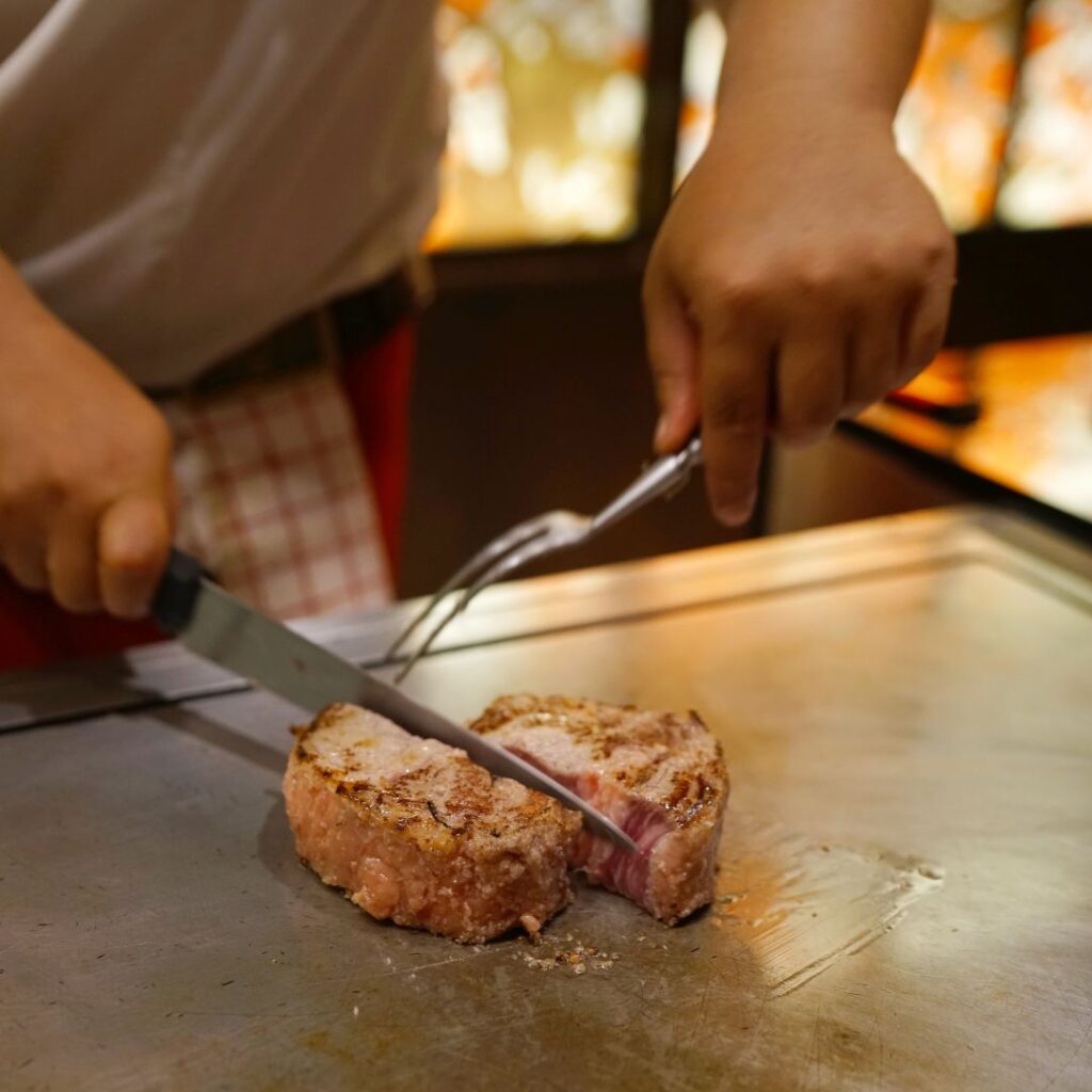 man slicing steak with koji